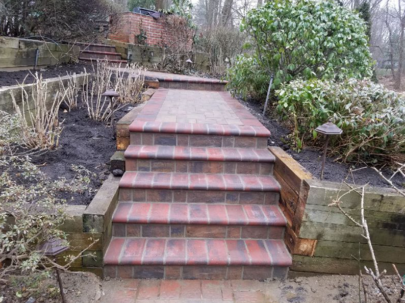 Brick steps and pathway ascend through a garden.