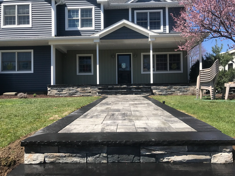 Stone walkway leading to a house with a blue and green facade.