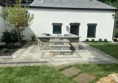 Backyard patio with stone hot tub, steps, and patterned pavers.