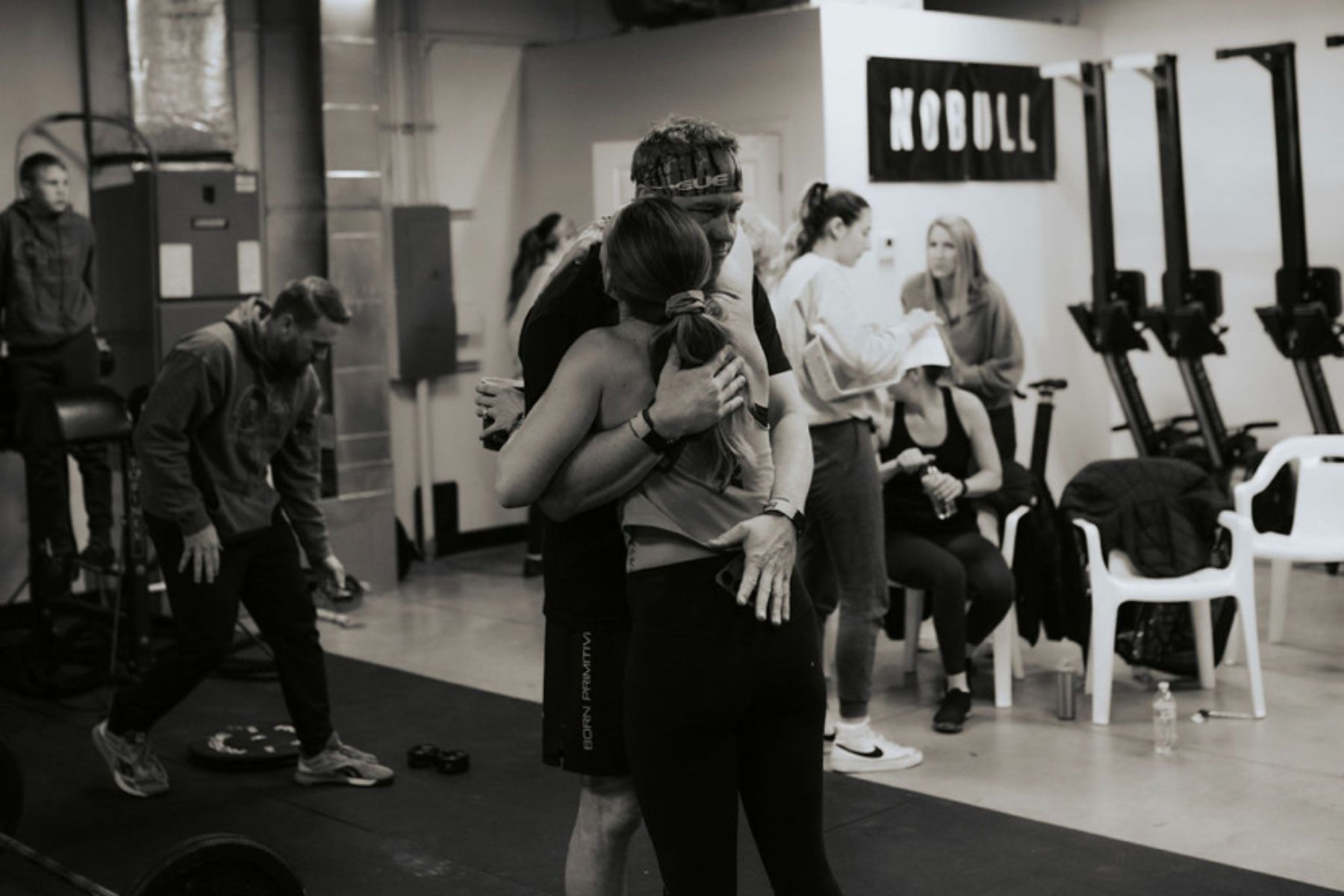 A black and white photo of a group of people hugging in a gym.
