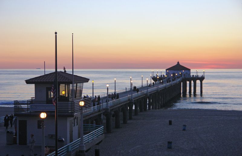 A pier at sunset with a lifeguard tower in the foreground