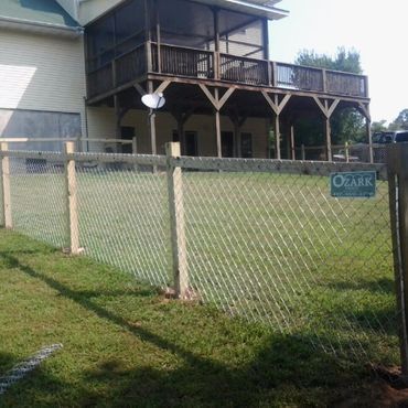 Chain-link fence in front of a house with a porch. The sign reads 