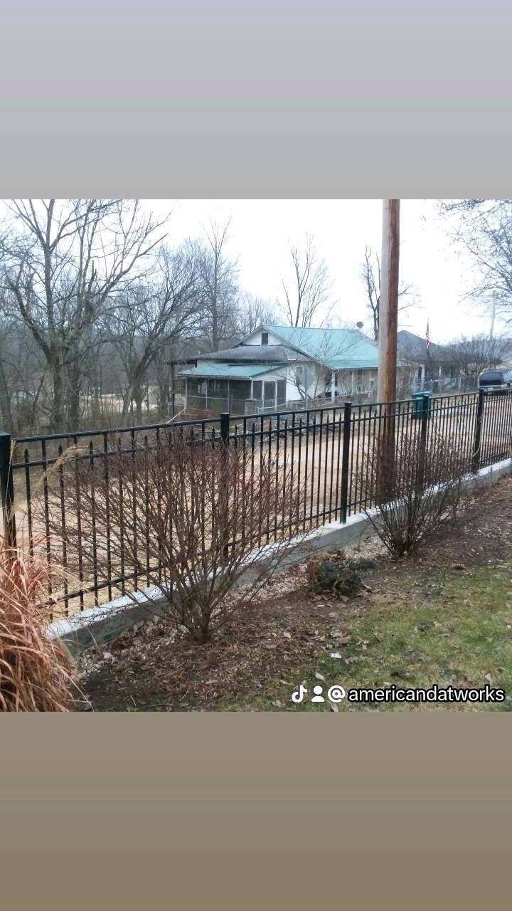 Rustic house behind a rusty fence on a rainy, leafless suburban street