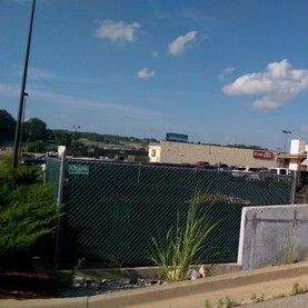 A tall chain-link security fence enclosing a commercial storage yard under a clear blue sky