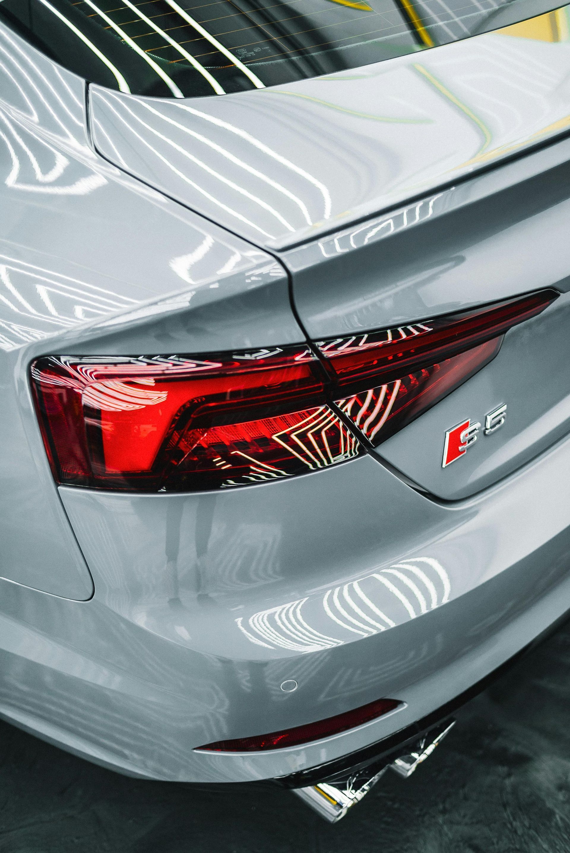 A close up of the back of a silver car with a red tail light.