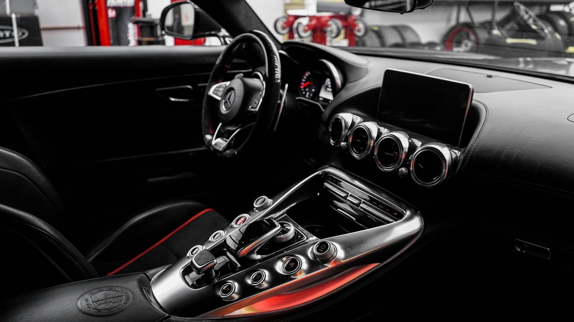 The interior of a black sports car with a steering wheel and dashboard.