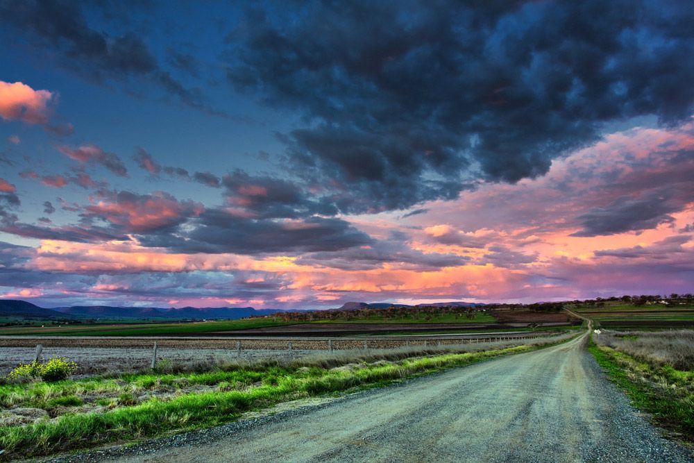 A Dirt Road Going Through a Field with A Sunset in The Background — Solar Blessing in Warwick, QLD