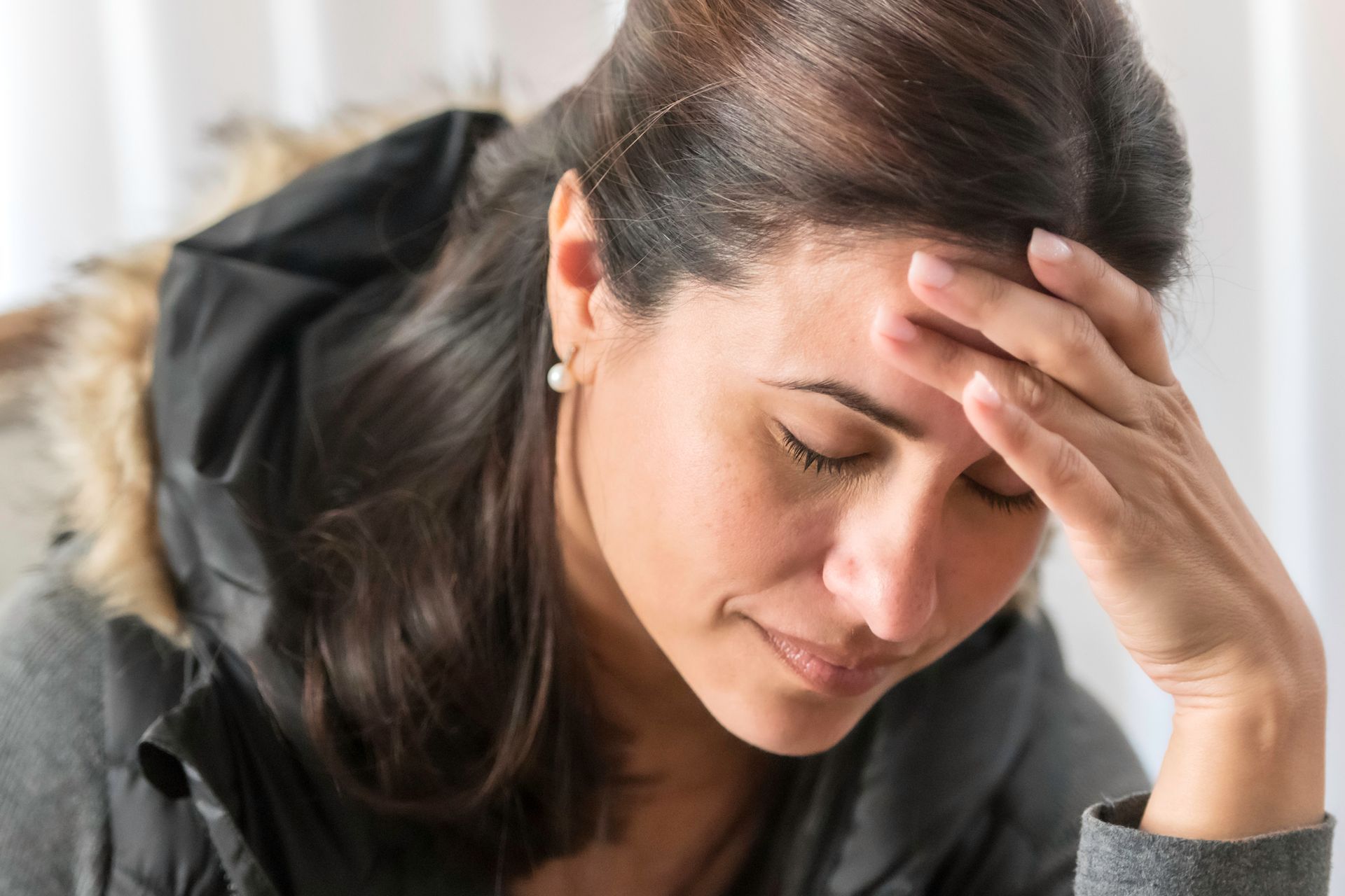 A woman is holding her head with her hand.