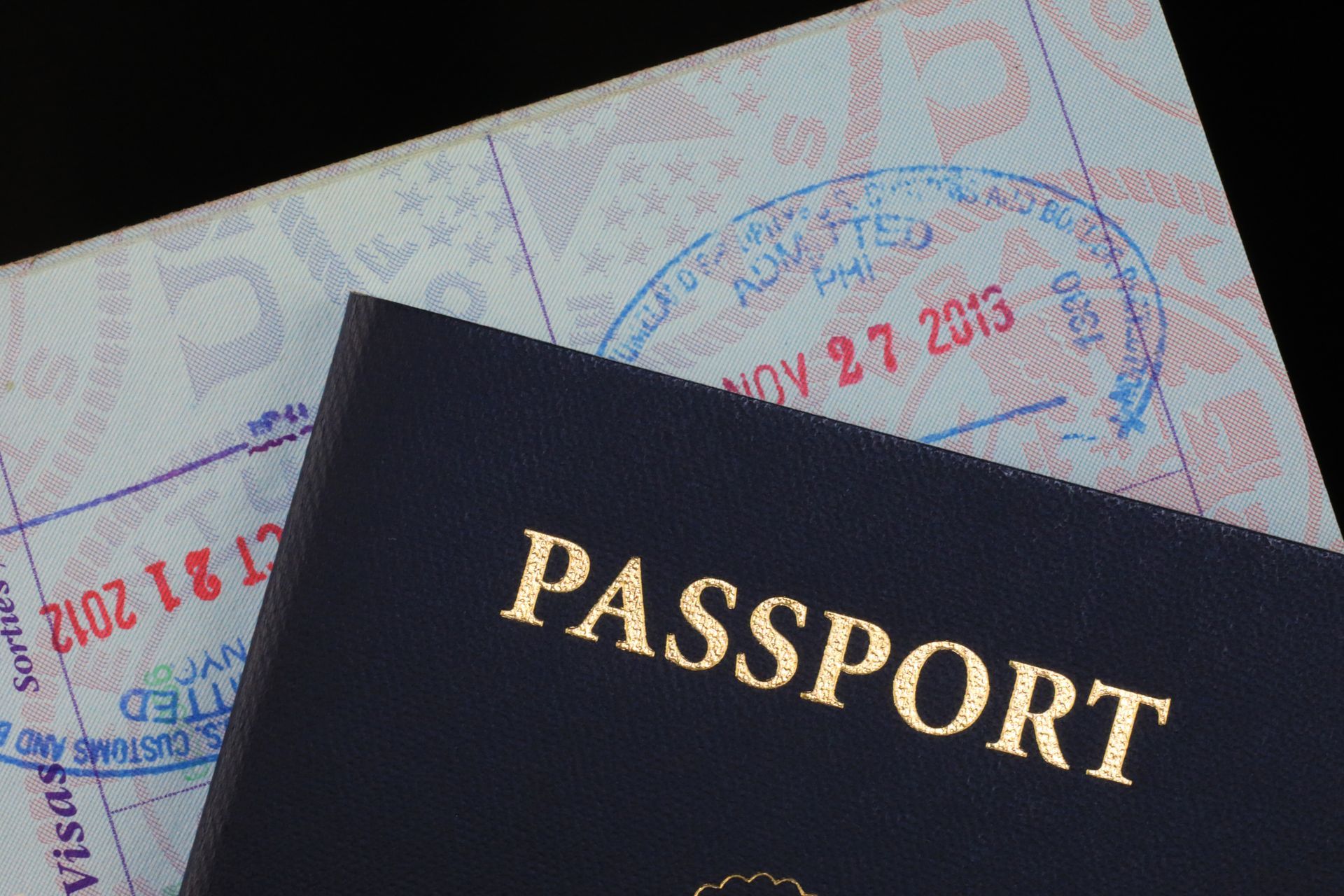 A blue passport is sitting on top of a white passport.