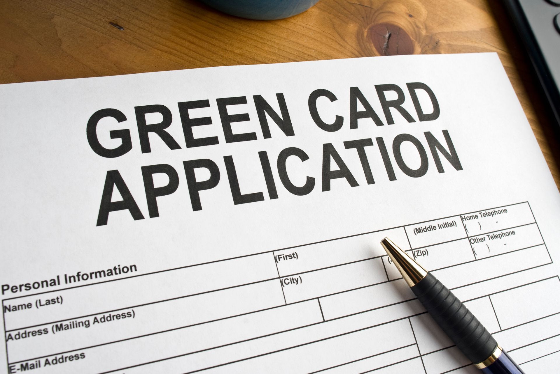 A green card application form with a pen on it.