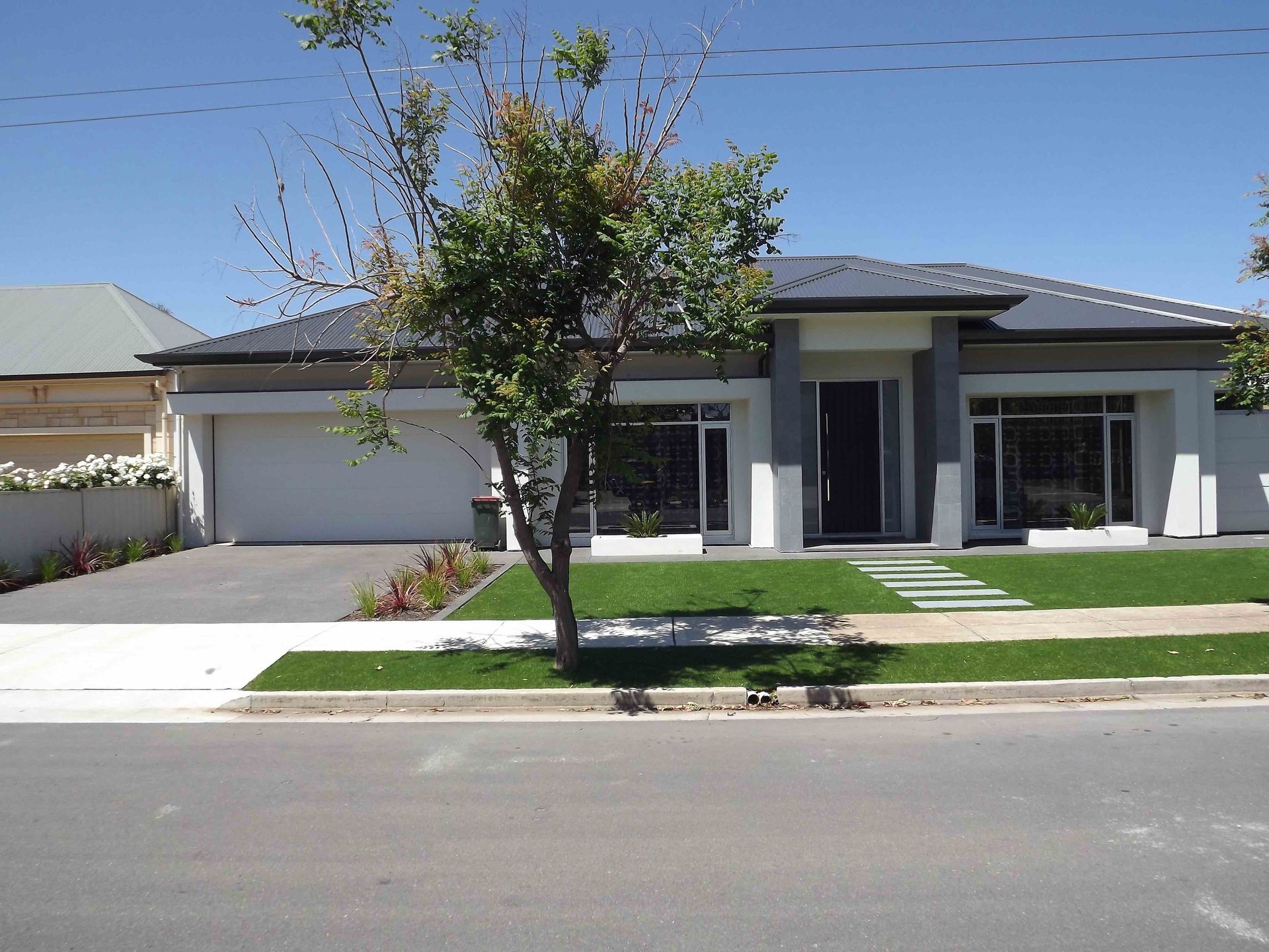 A concrete driveway leading to a house with two garage doors.