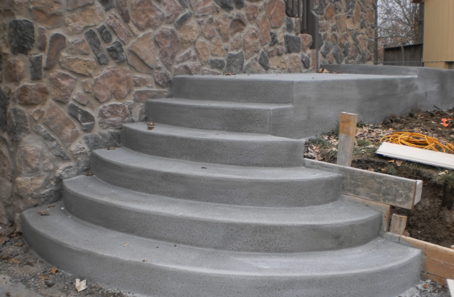 a set of concrete stairs being built in front of a stone wall .