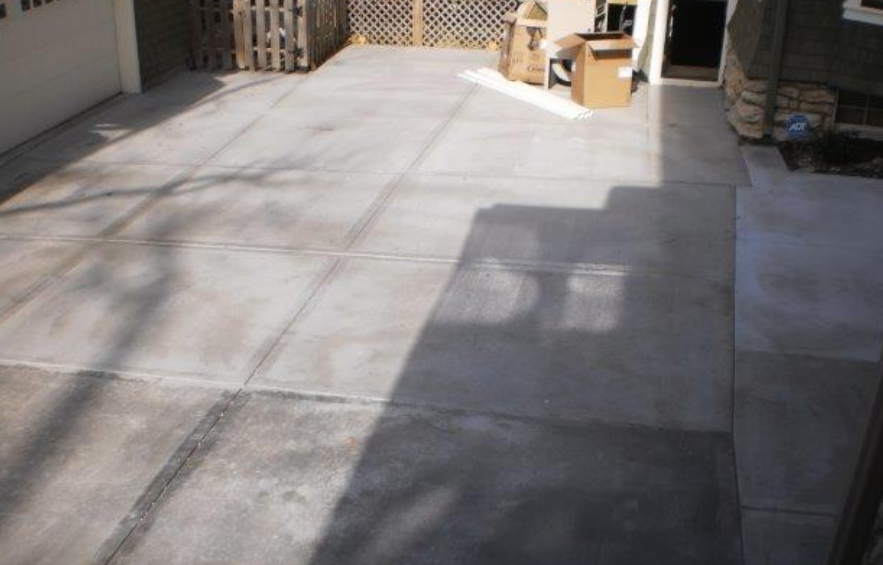 A concrete driveway with a shadow of a tree on it