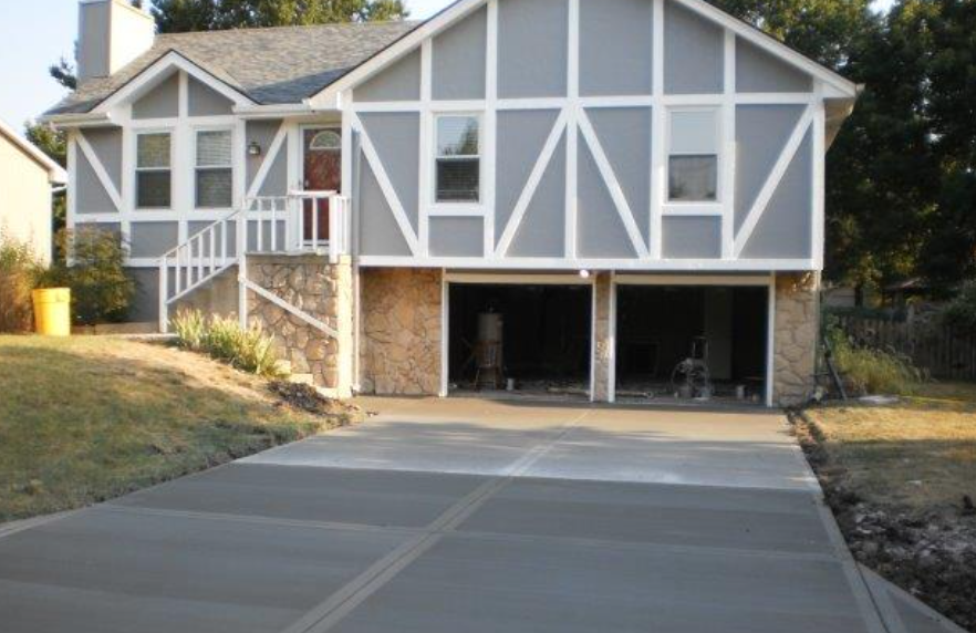 a large house with a concrete driveway in front of it