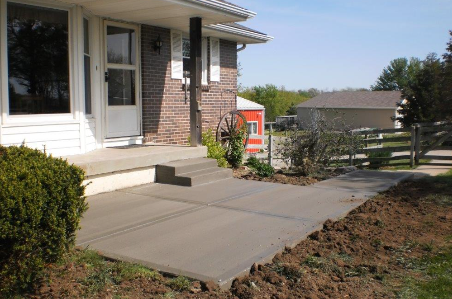 a brick house with a concrete walkway in front of it