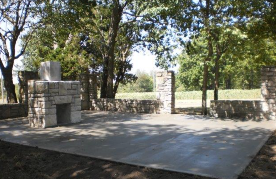 a patio with a fireplace and trees in the background