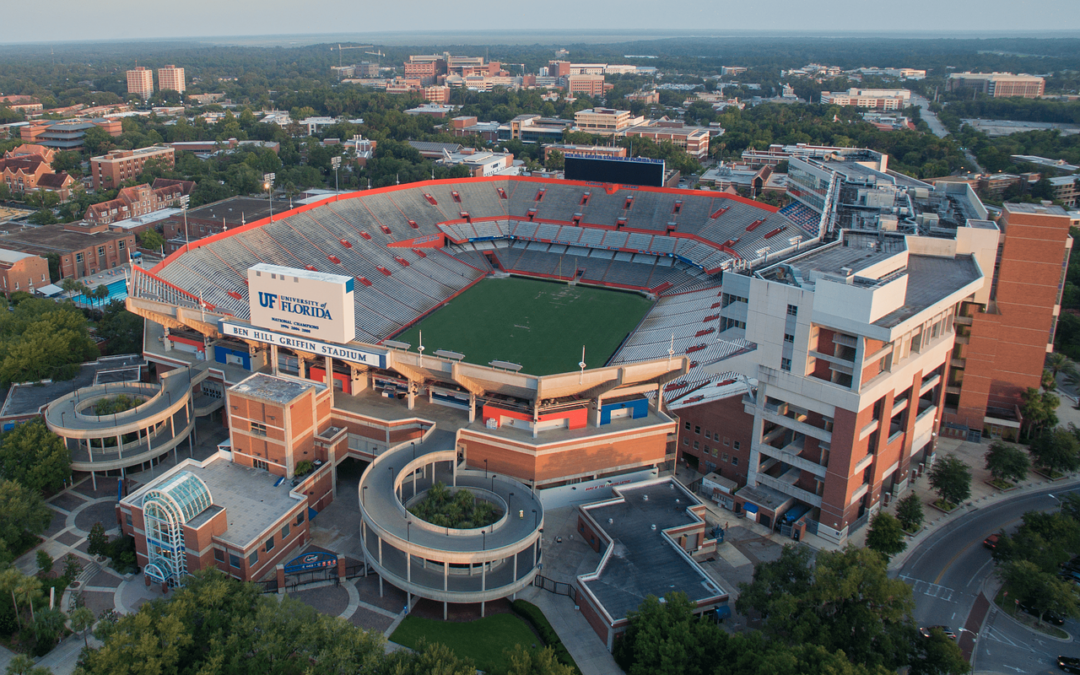 Aerial view of the University of Florida's football stadium, Ben Hill Griffin Stadium, surrounded by buildings and trees.