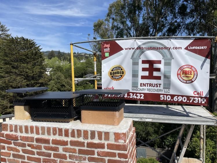 Chimney with two black caps; scaffolding with a company sign in a residential setting.