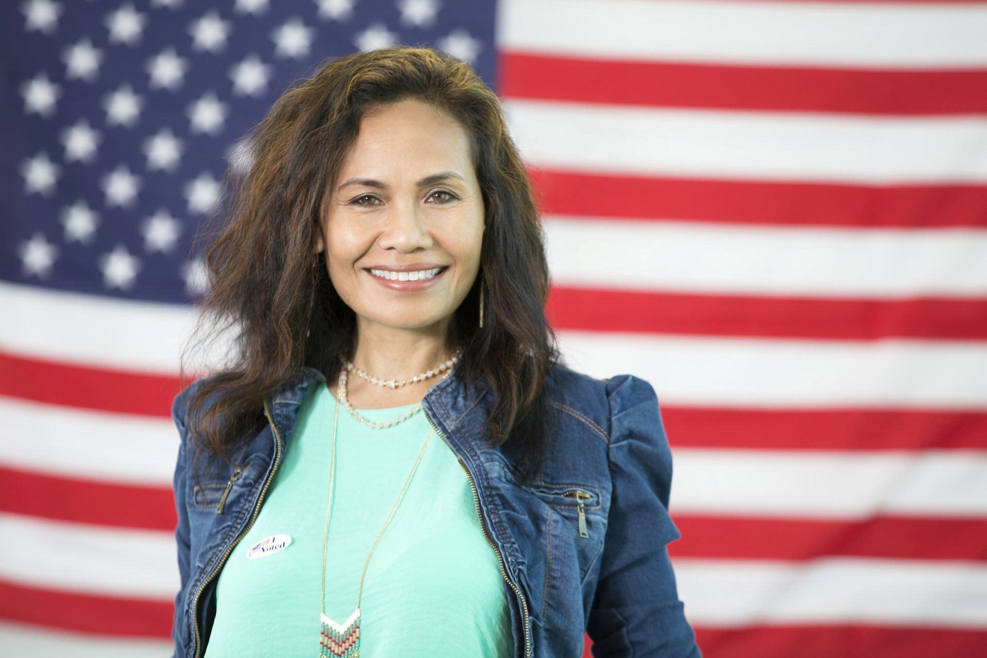 a woman is standing in front of an american flag and smiling
