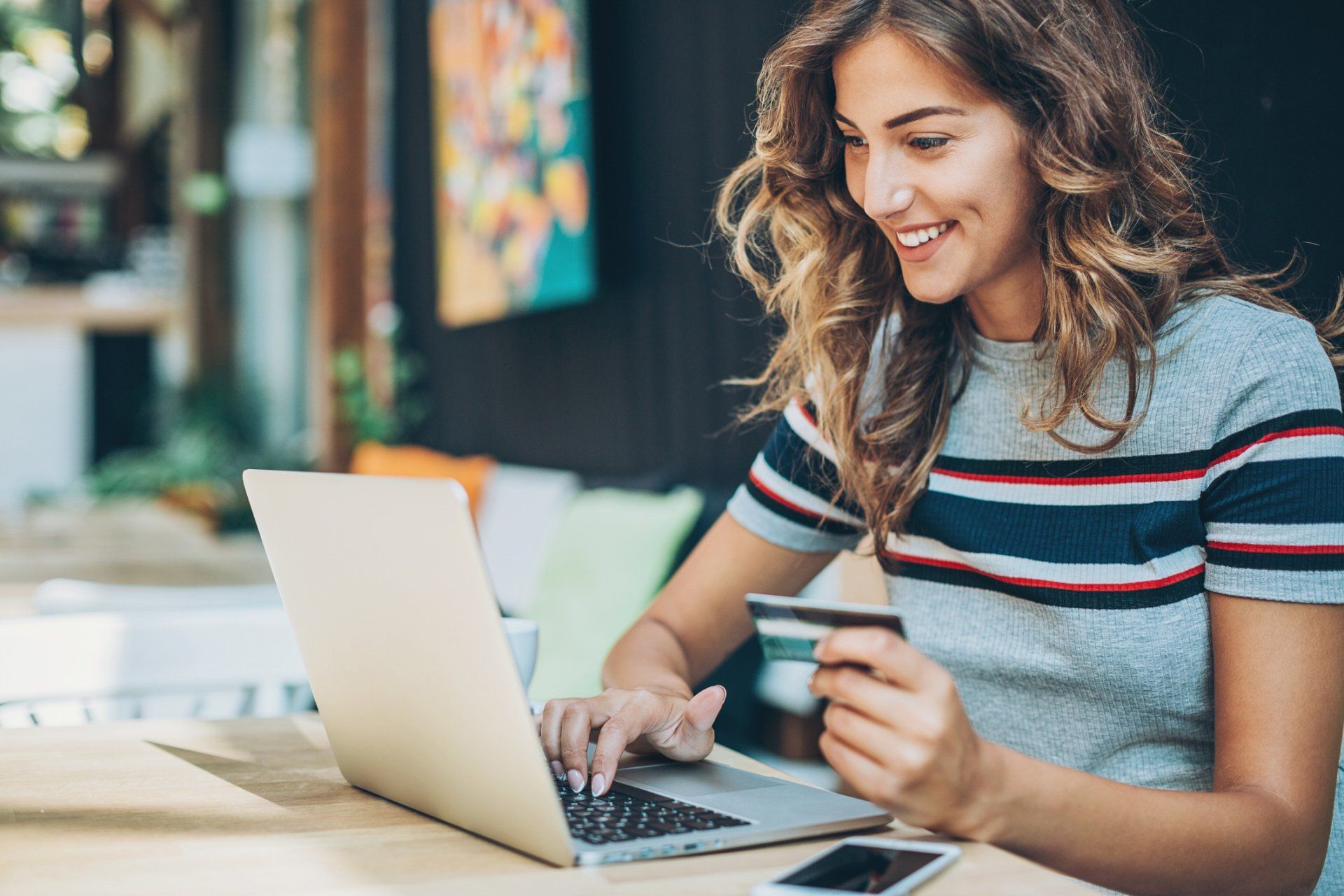 a woman is holding a credit card and using a laptop computer