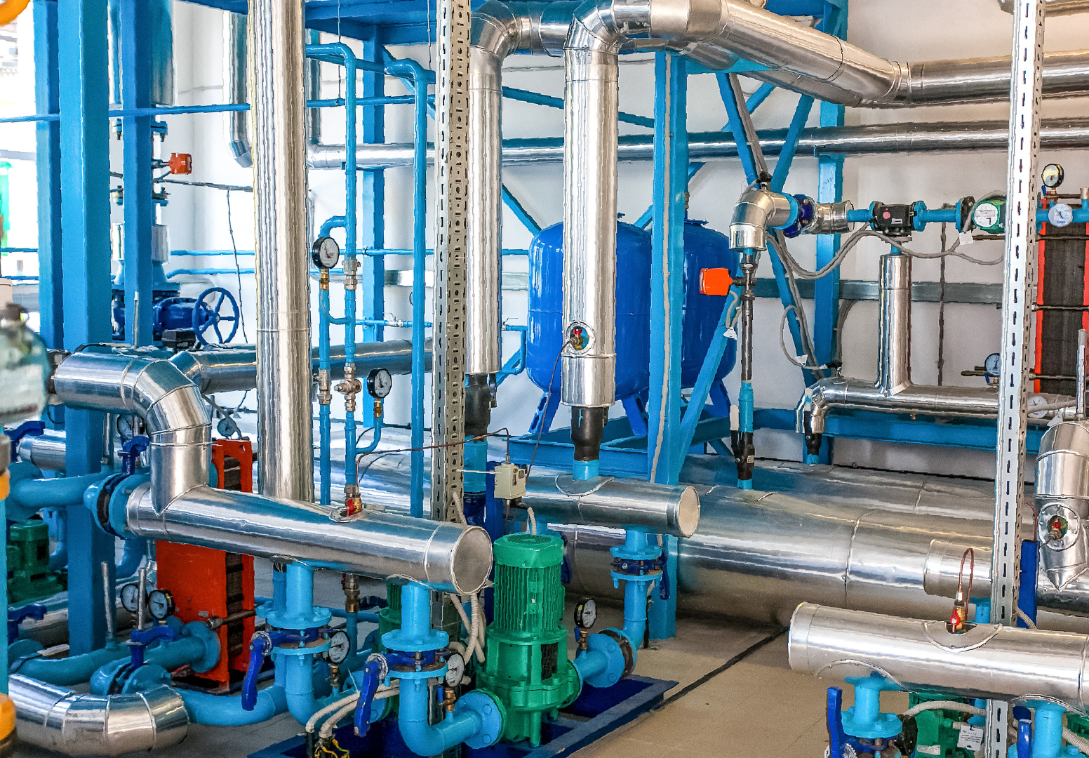 A room filled with lots of pipes and pumps in a factory.