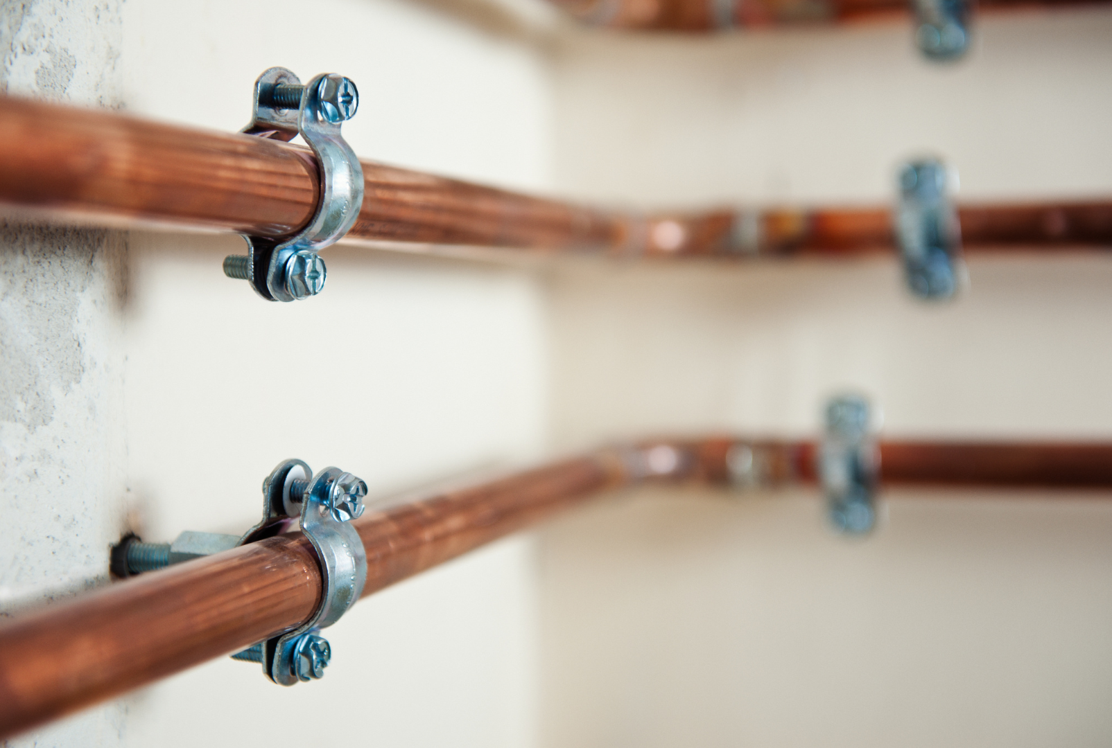 A close up of copper pipes attached to a wall.