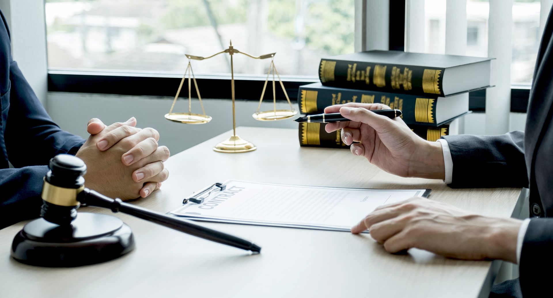 Lawyers discussing a case at a desk with gavel, scales of justice, and legal books
