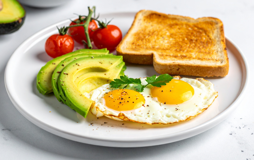 Avocado toast with two fried eggs and cherry tomatoes on a white plate