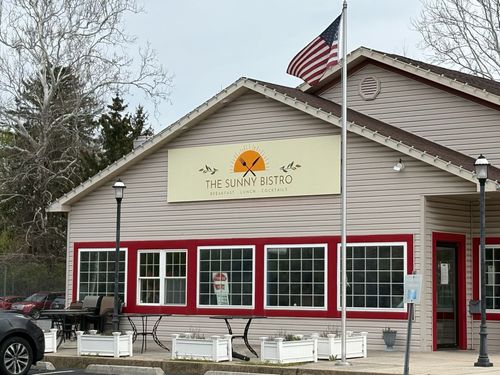 Small beige storefront with red-trimmed windows and an American flag outside