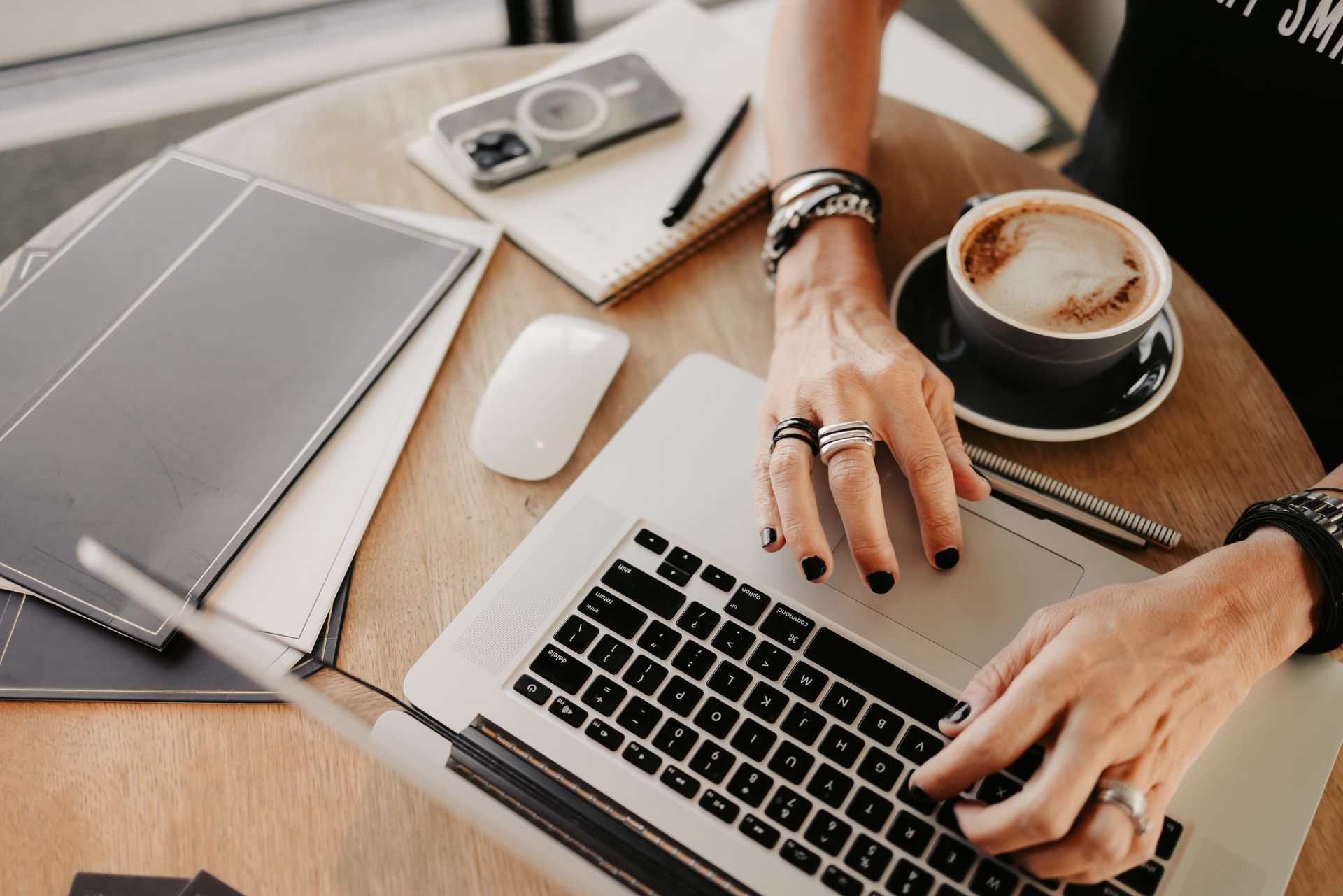 A woman is sitting at a table with a laptop and a cup of coffee.