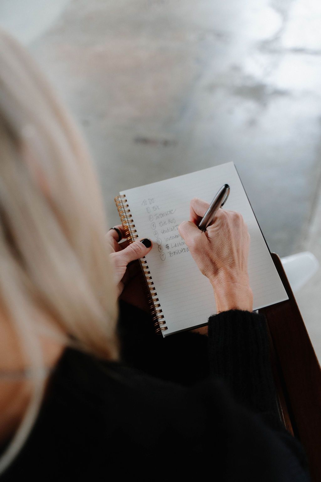 A woman is writing in a notebook with a pen.