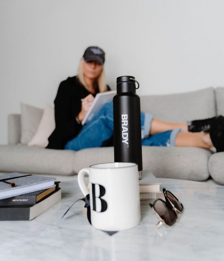 A woman sits on a couch next to a brady water bottle