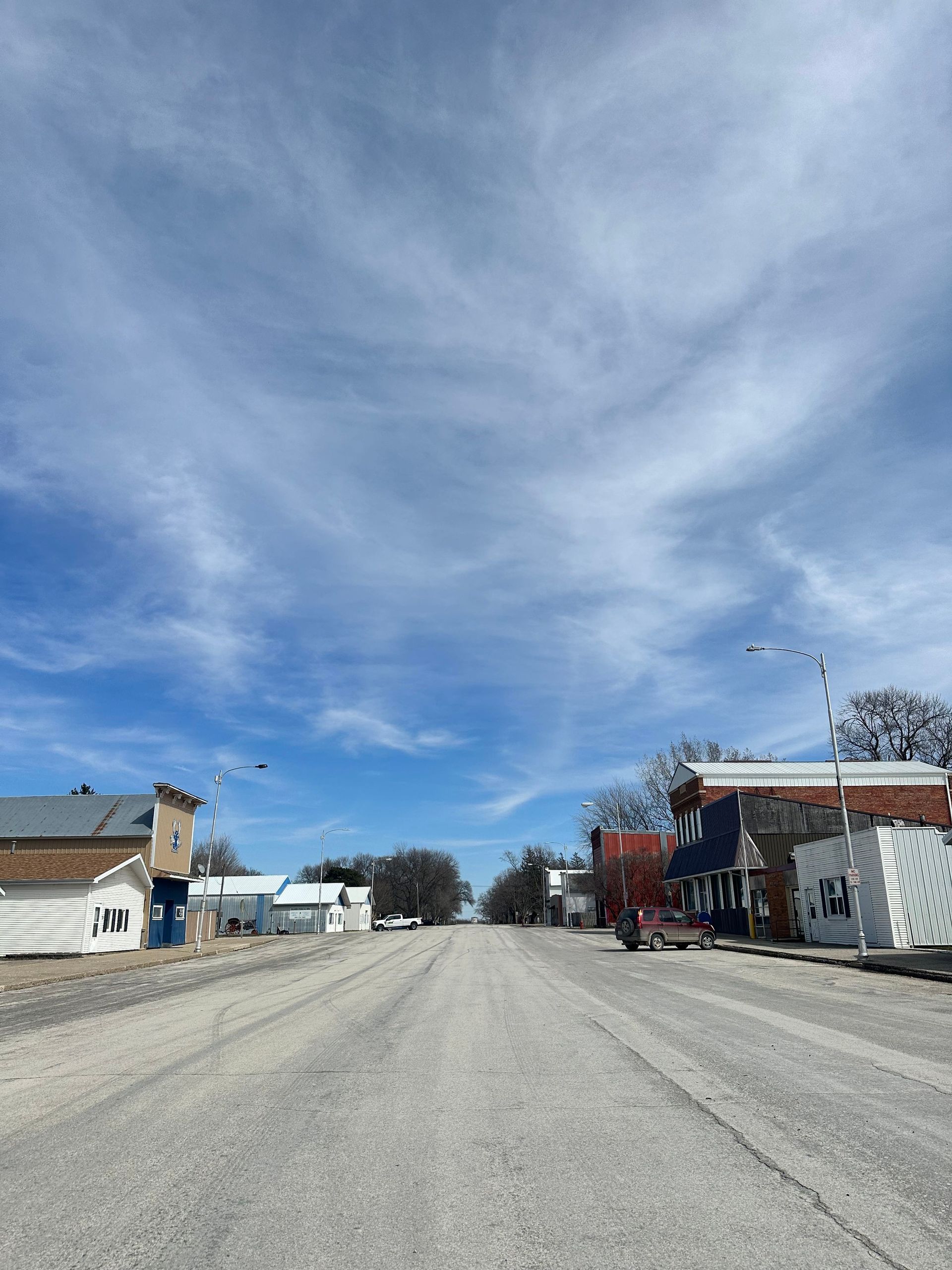 A street with a lot of buildings on it and a blue sky with clouds.