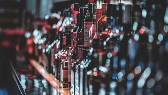 A row of bottles of alcohol are lined up on a bar.