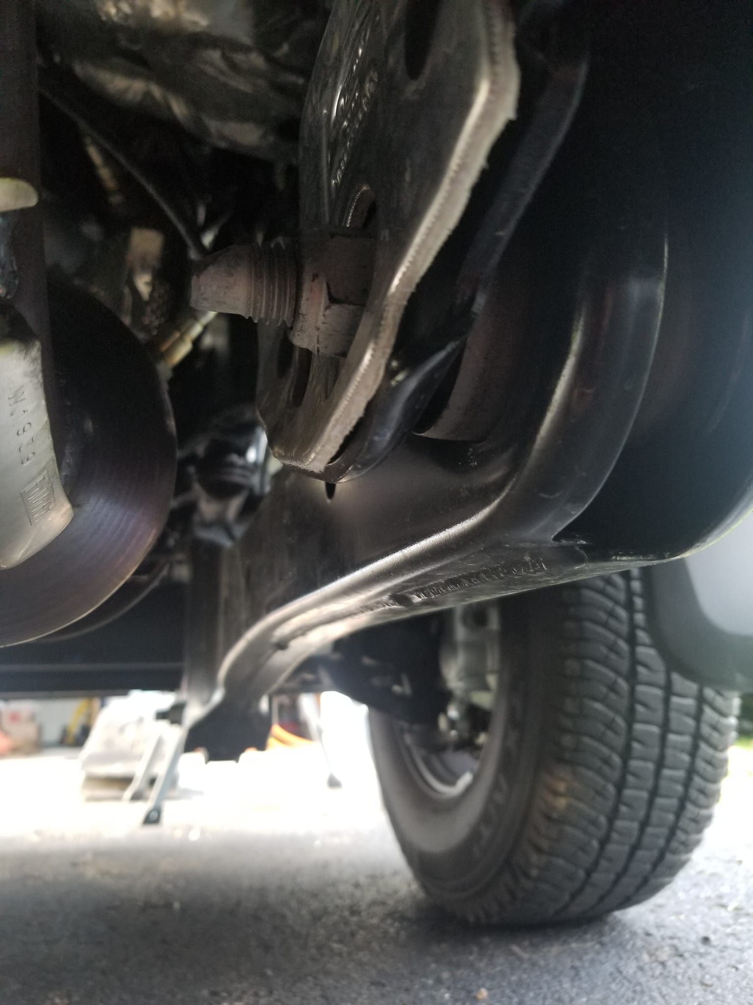 Underneath a vehicle, close-up of suspension and a rear tire on pavement