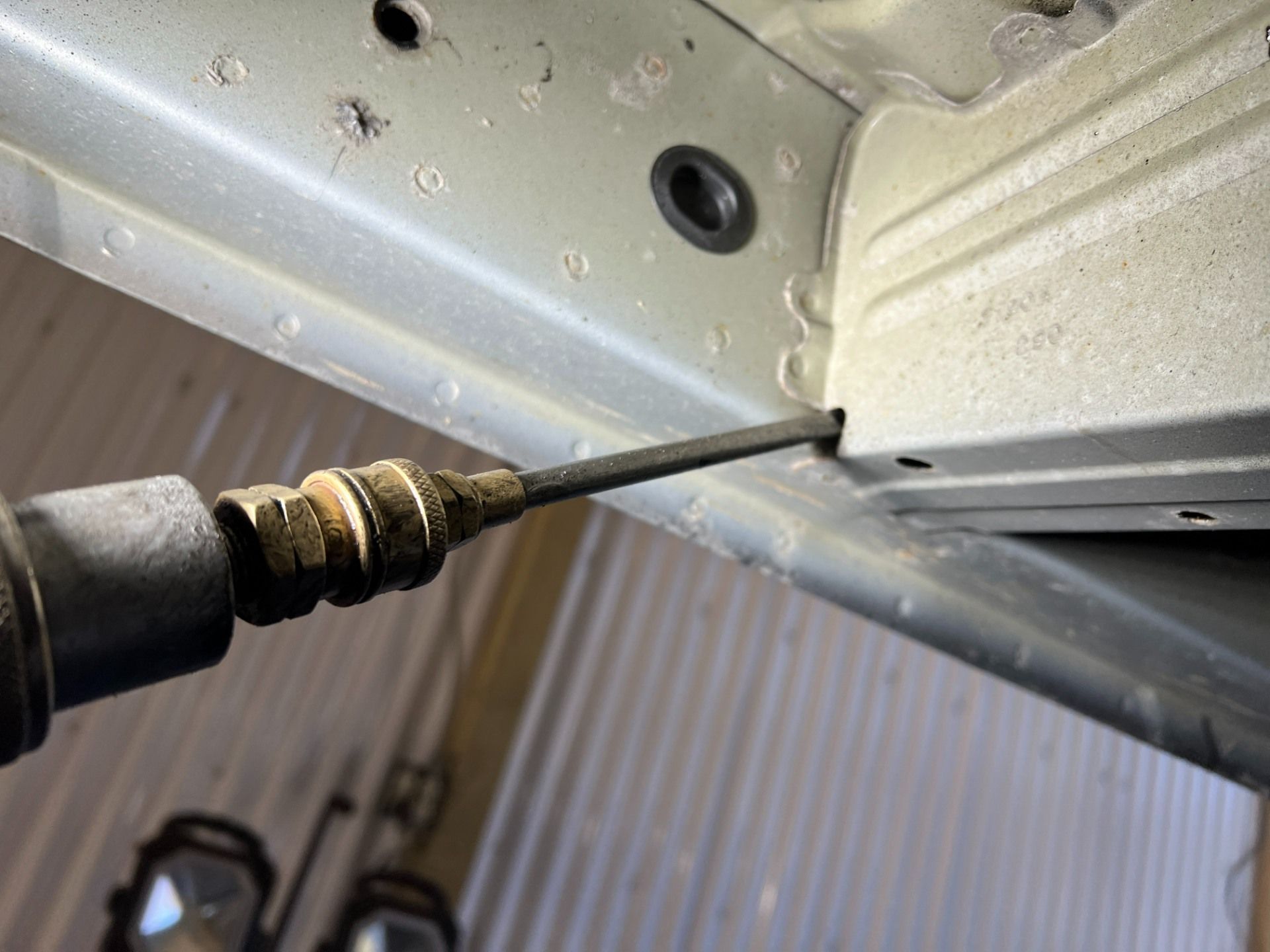 Close-up of a screwdriver tightening a screw on a metal panel underside
