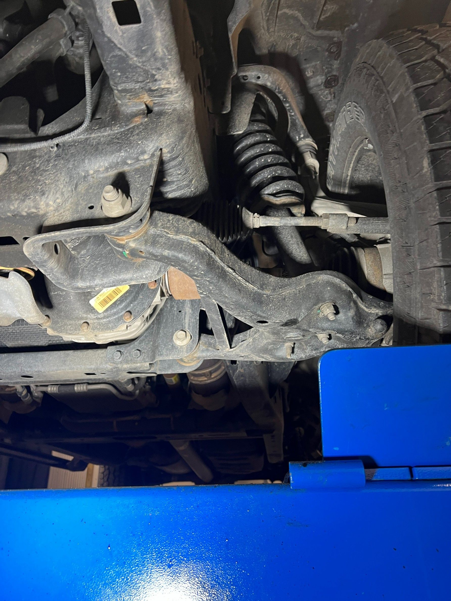 Car suspension and coil spring above a blue lift in an auto repair shop