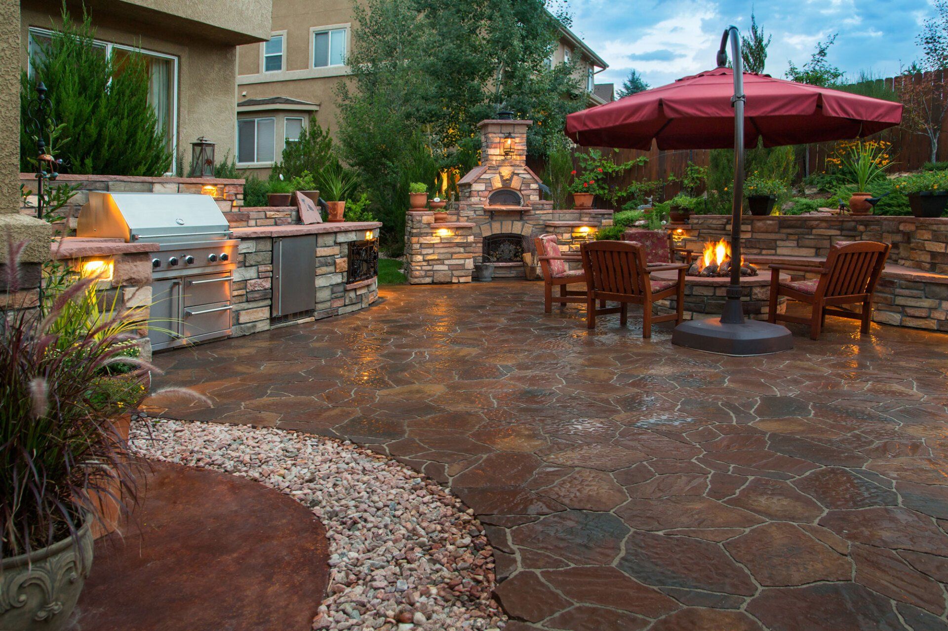 A patio with a red umbrella and a grill