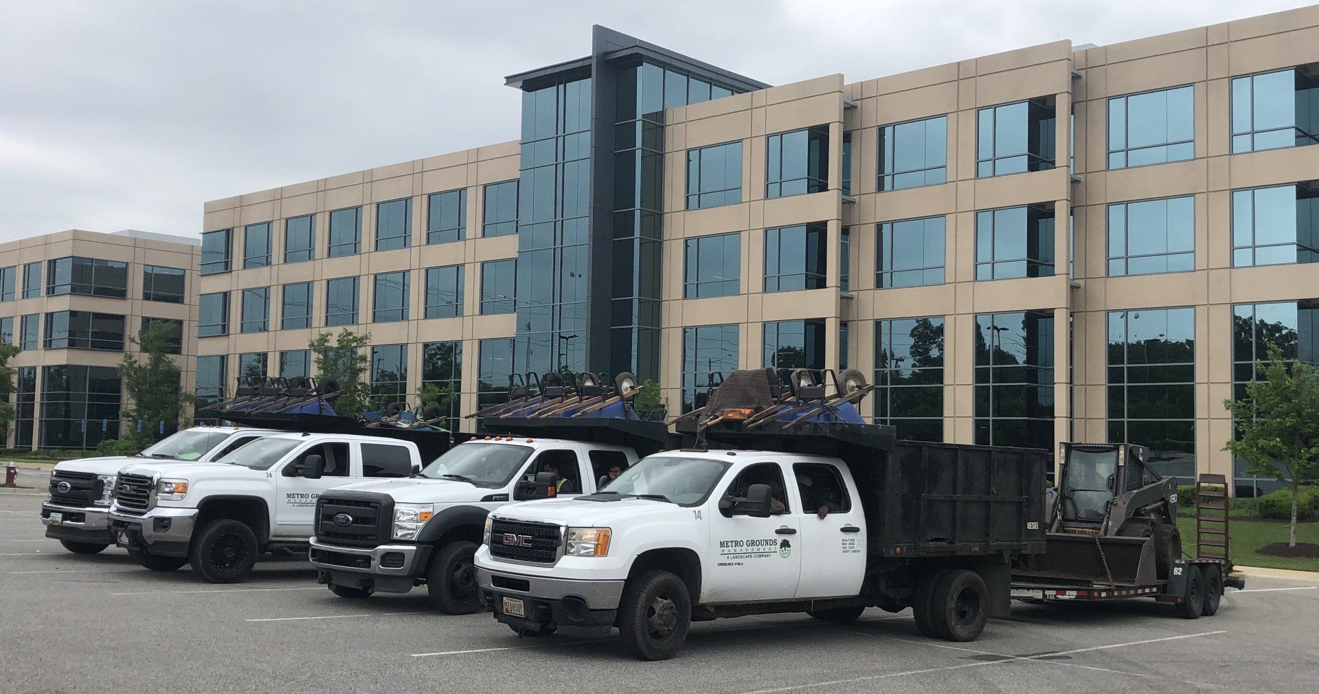 A row of trucks are parked in front of a large building.