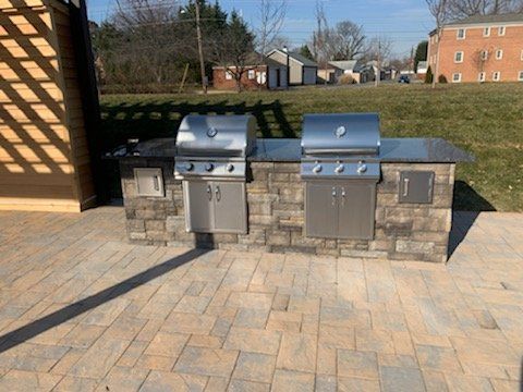 A grill is sitting on top of a brick patio.