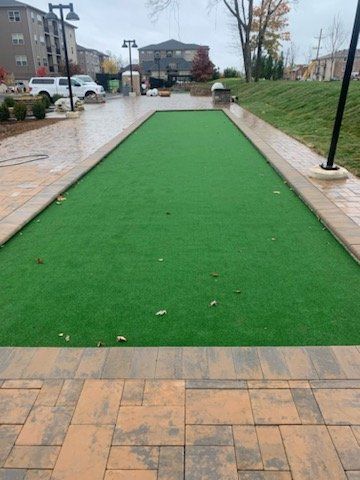 A green lawn with a brick walkway and a building in the background.