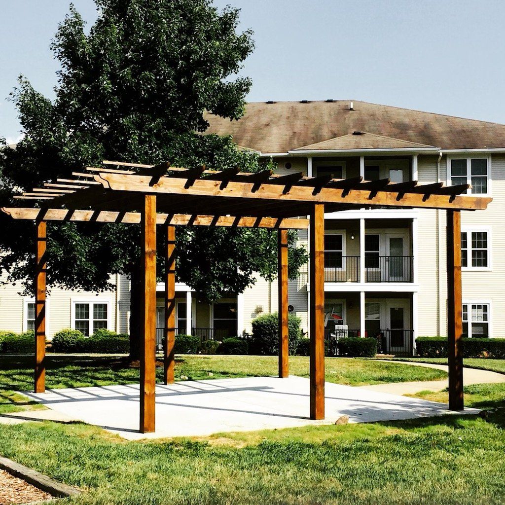 A wooden pergola is in front of a building