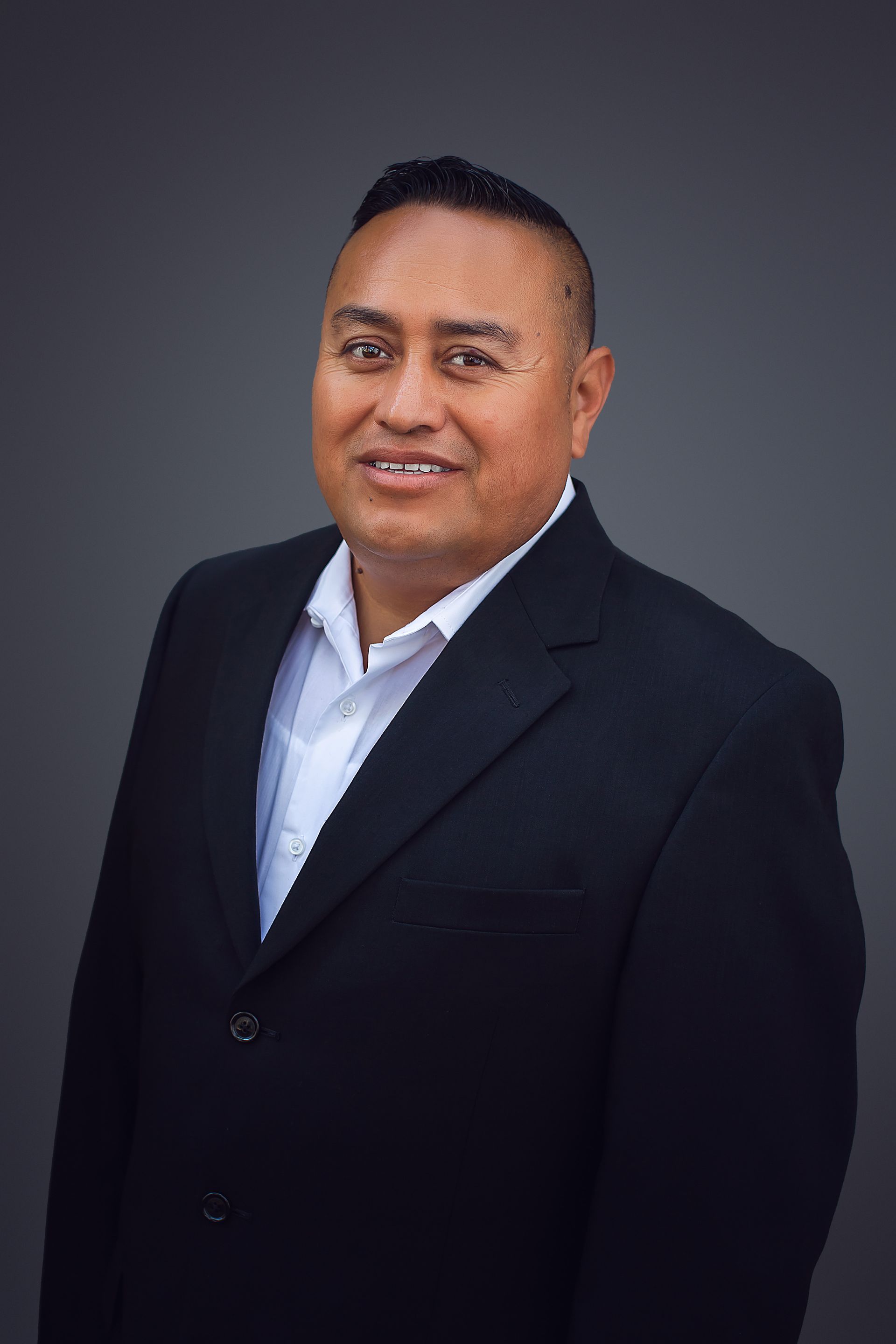 A man in a suit and white shirt is smiling for the camera.