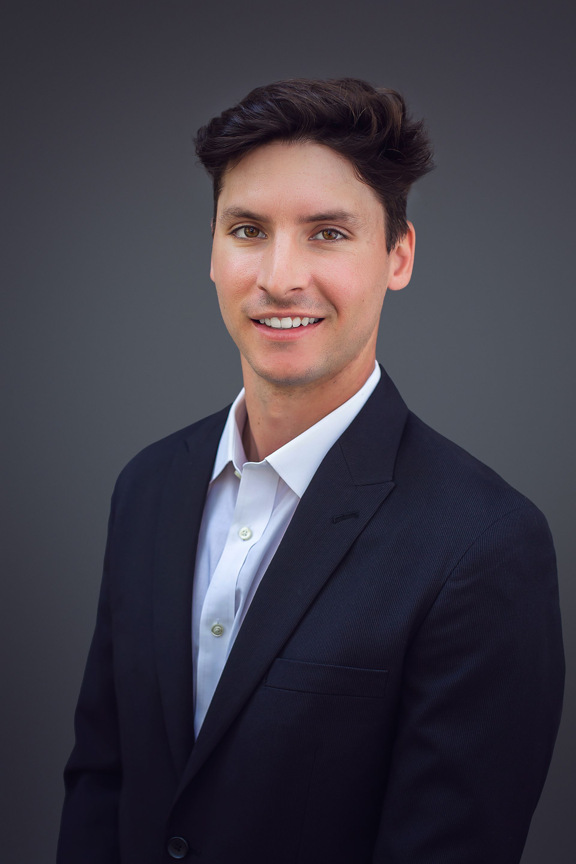A man in a suit and white shirt is smiling for the camera.