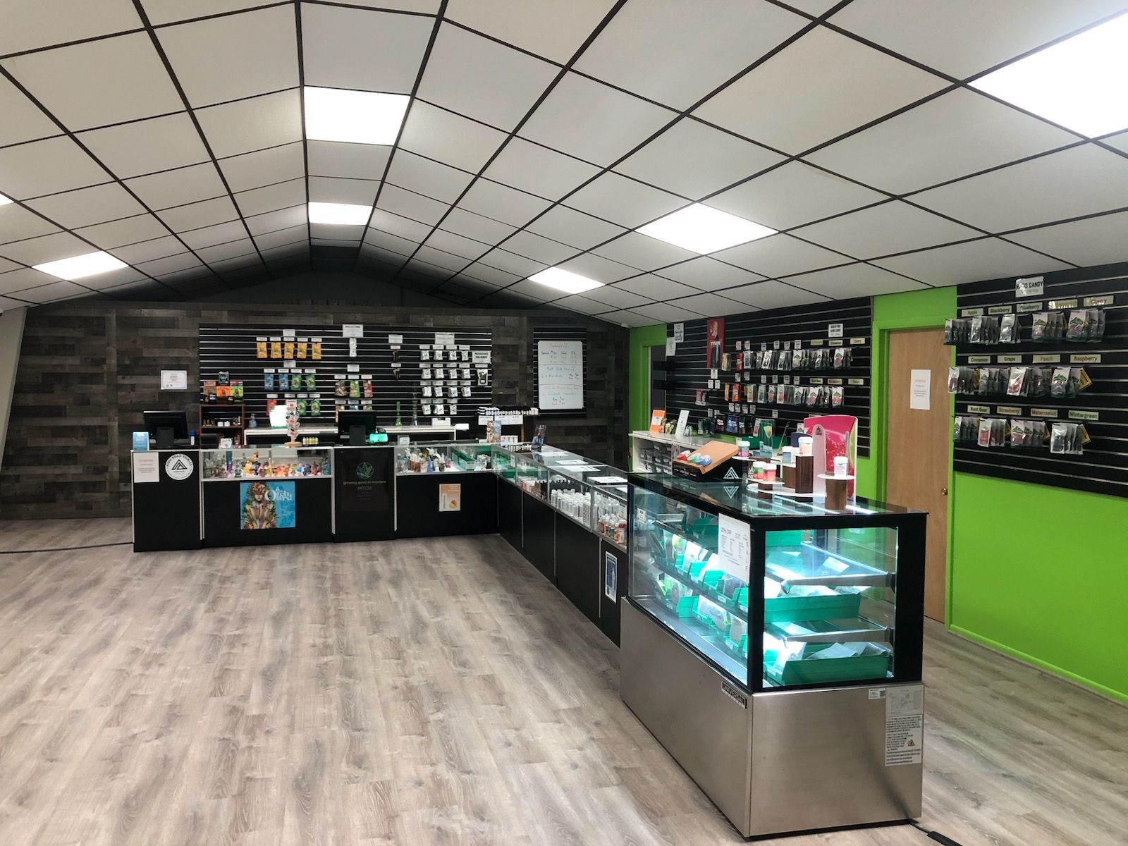 Interior of a cannabis dispensary with display cases, products, and a lime green wall.
