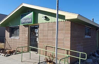 A small brown building with a green sign that says elevated on it.