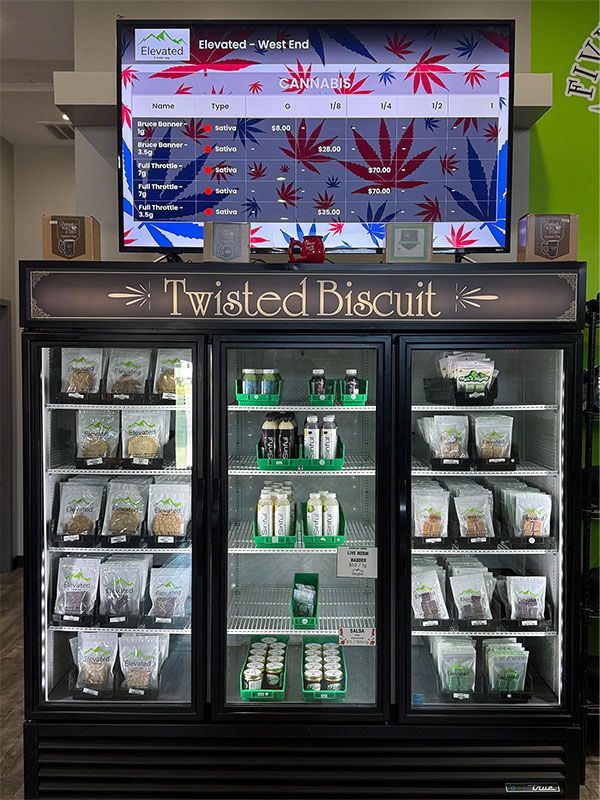 A black refrigerator display with cannabis products, under a sign for 