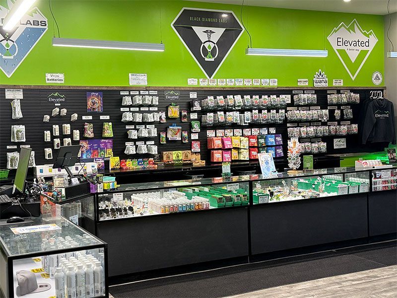 Inside a brightly lit cannabis dispensary, showcasing products on display counters and walls.