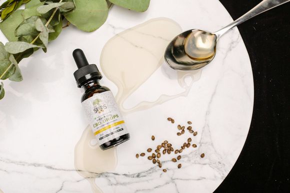 A bottle of oil next to a spoon on a plate.