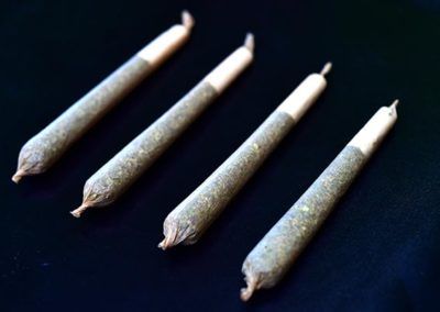 Four rolled cannabis joints on a dark surface, ready for use.